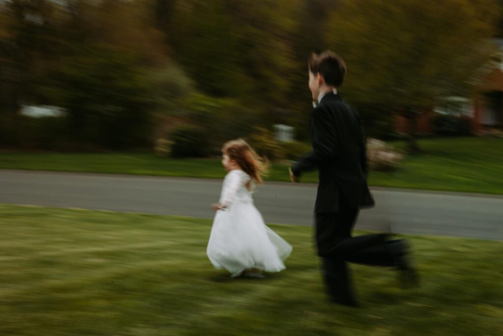 Flower girl running across the lawn in motion blur, candid wedding moment