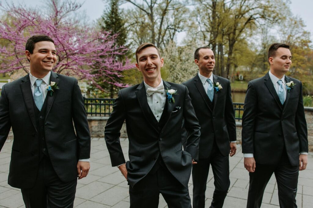Groomsmen standing together outside with pink flowering trees, Elizabeth Park spring wedding