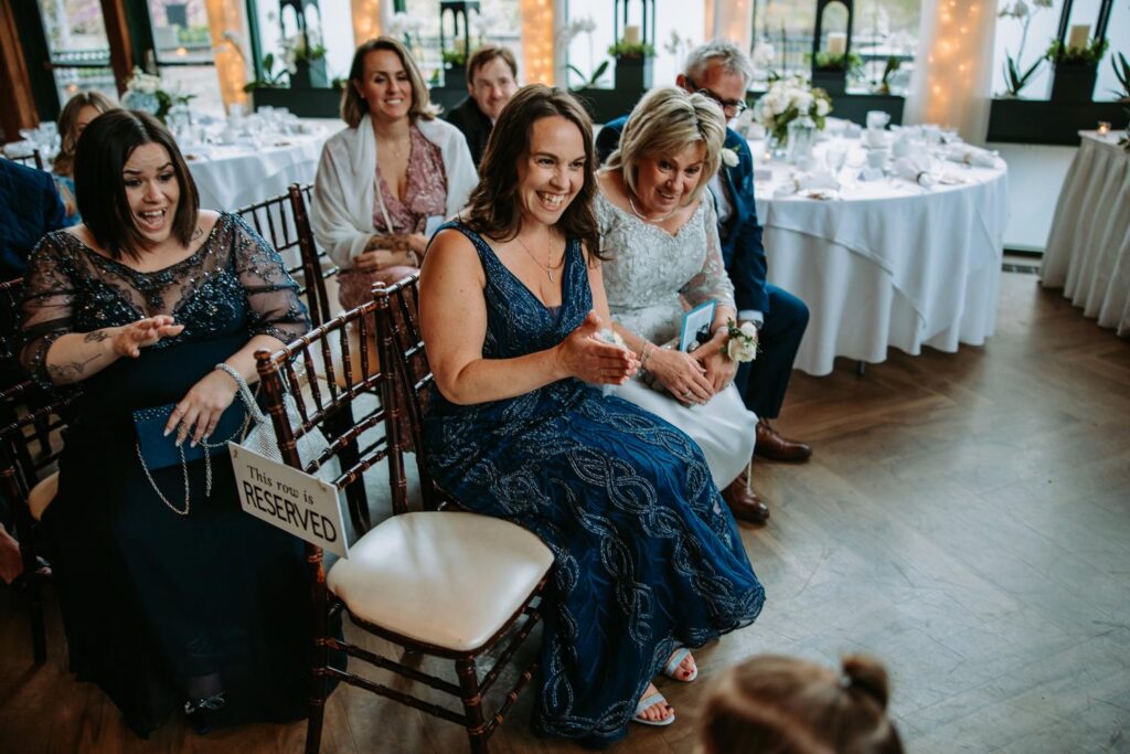 Family members laughing and reacting together during wedding reception at Elizabeth Park