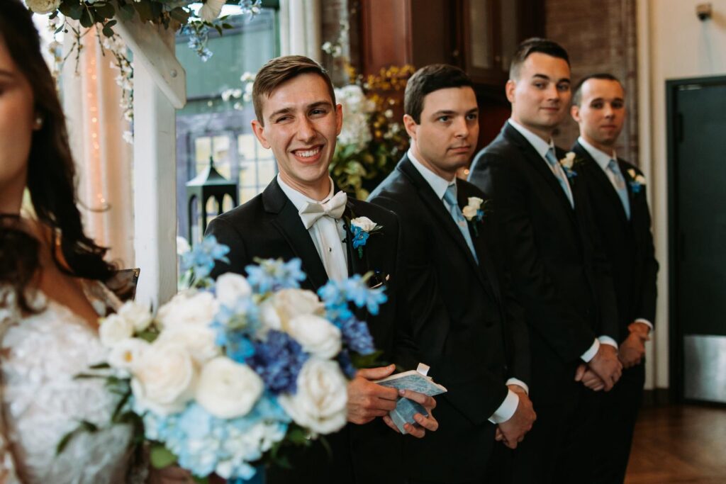 Groom and groomsmen smiling during wedding ceremony at The Pond House Cafe
