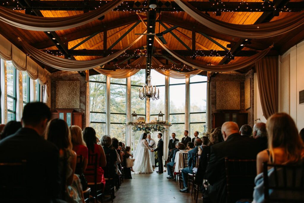 Wedding ceremony wide shot showing cathedral windows and floral arch, Elizabeth Park West Hartford