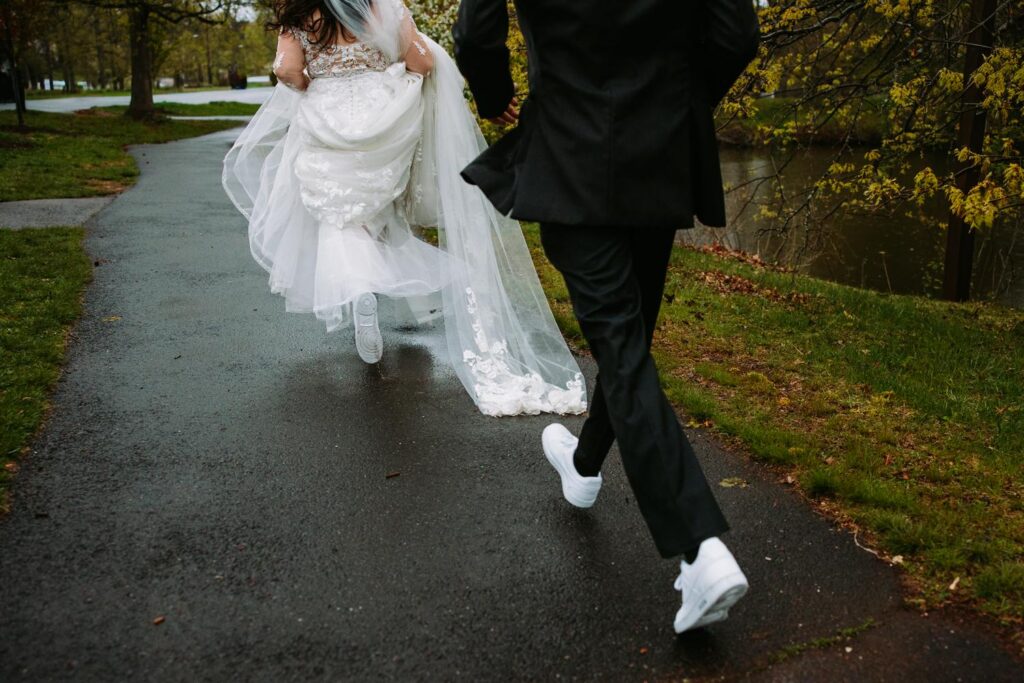 Bride and groom running through rain at Elizabeth Park, candid wedding portrait moment
