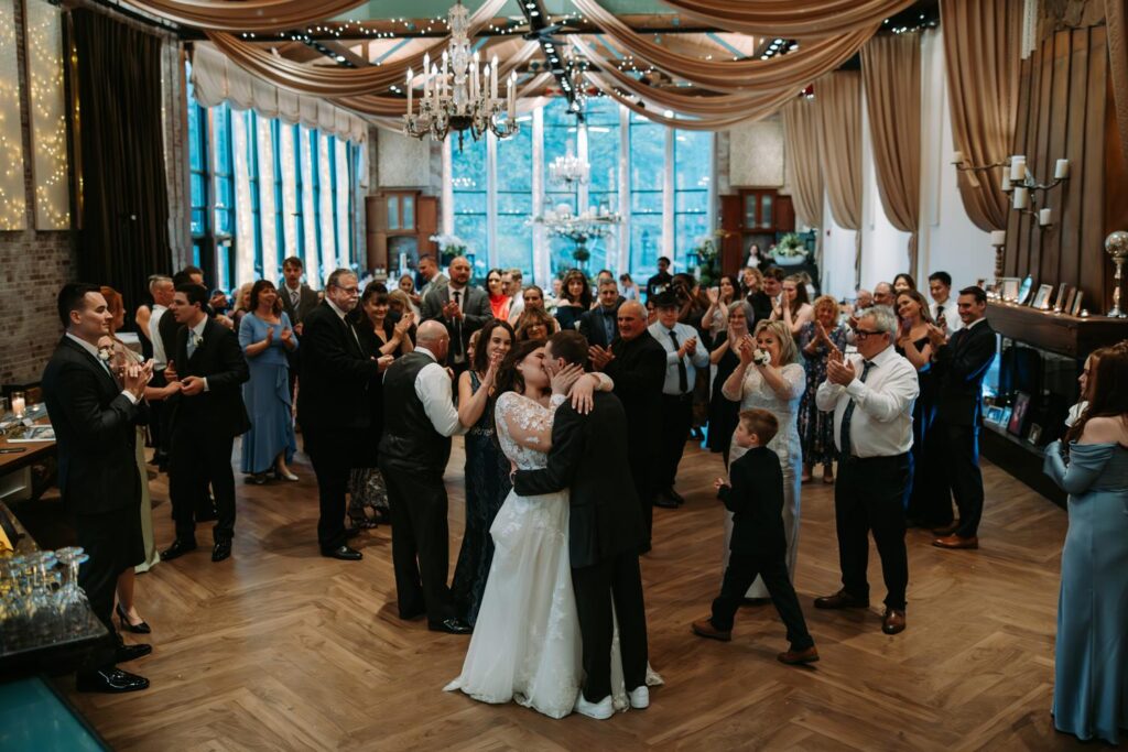 Wide shot of first dance at Pond House Cafe with warm chandelier lighting and full guest attendance