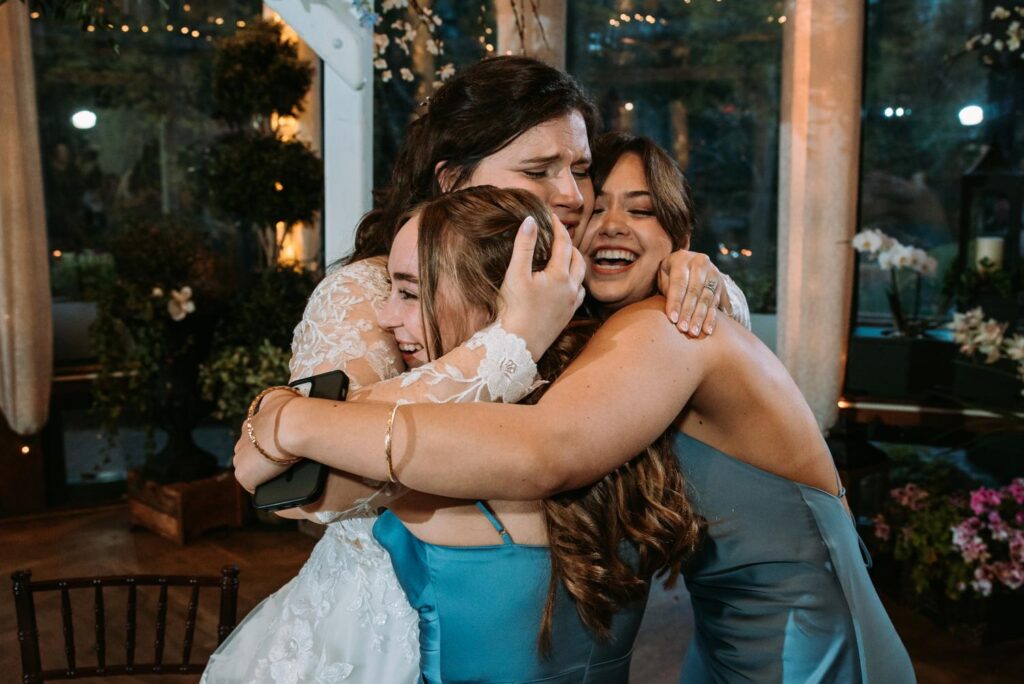 Bride and sister sharing an emotional tearful hug during wedding reception