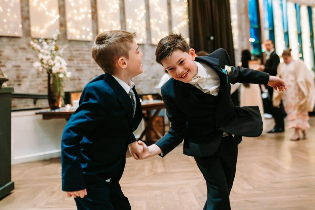 Two young boys goofing around on the wedding dance floor, candid moment