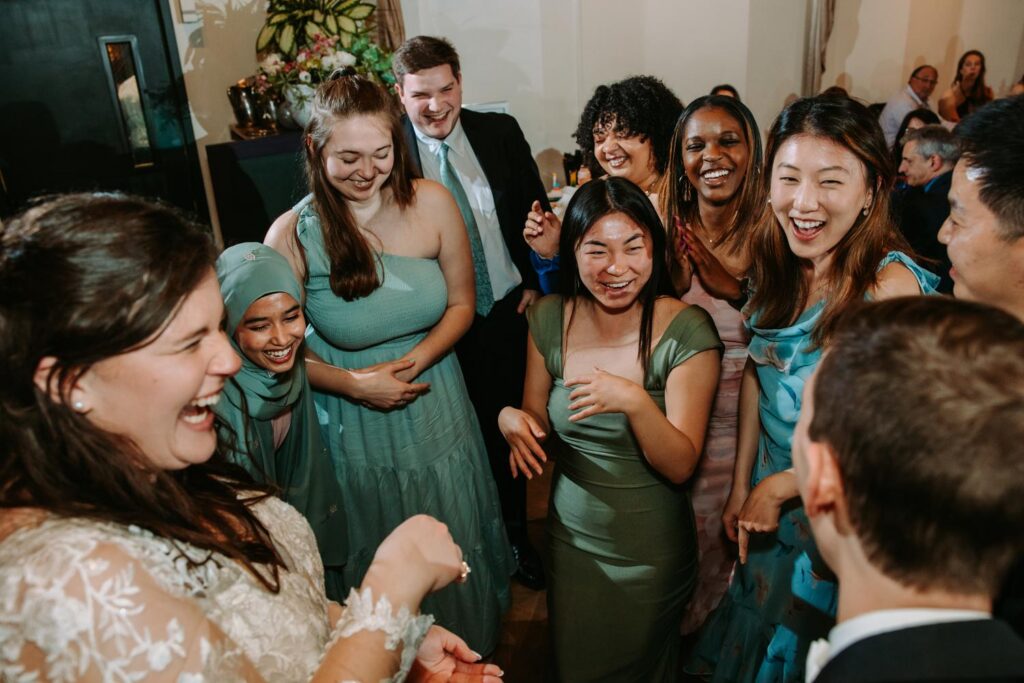 Large group of wedding guests laughing and celebrating together, documentary reception photo