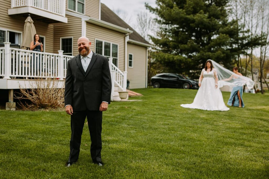 Bride walking across lawn toward father for their first look moment