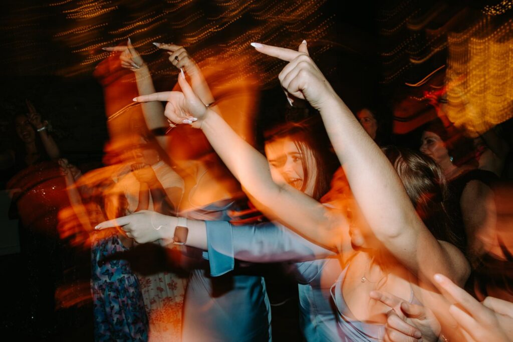 Motion blur dance floor shot with hands raised, high energy Pond House wedding reception