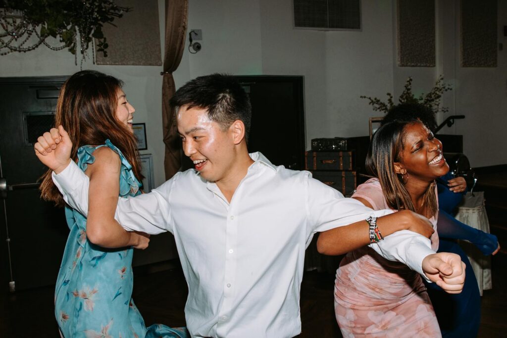 Diverse group of wedding guests dancing together on the Pond House Cafe dance floor
