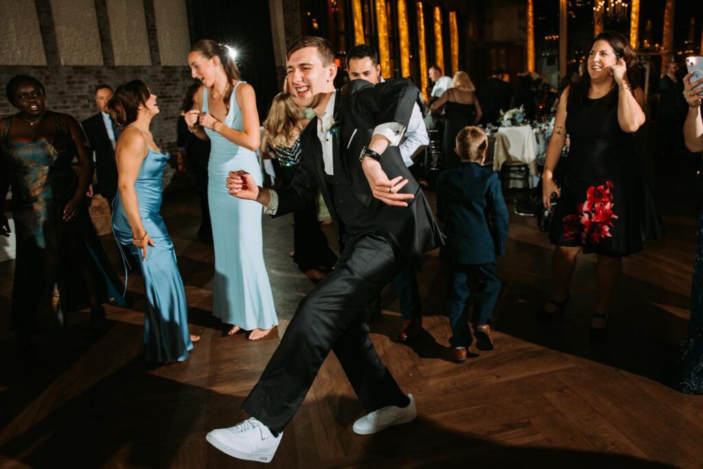 Groom showing off dance moves on the reception floor, candid fun wedding moment