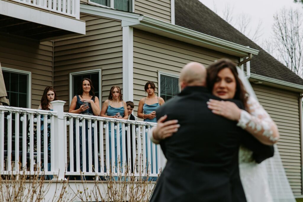 Bride and dad sharing an emotional hug with a family member before the wedding ceremony