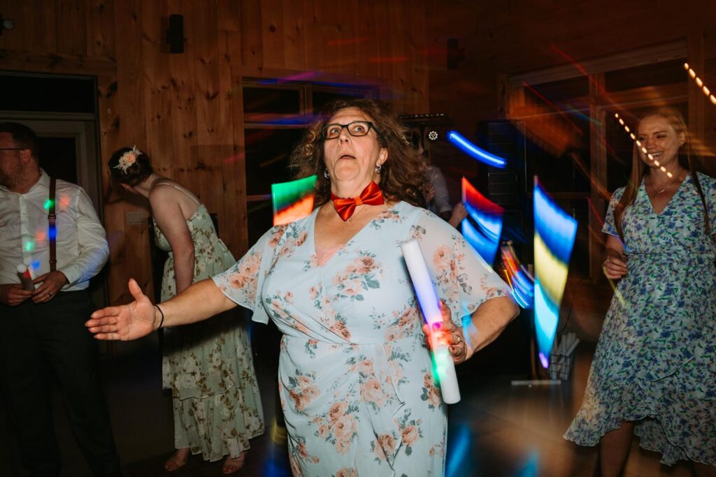 Groom's mom dancing with bowtie, completely in her element, candid documentary wedding moment