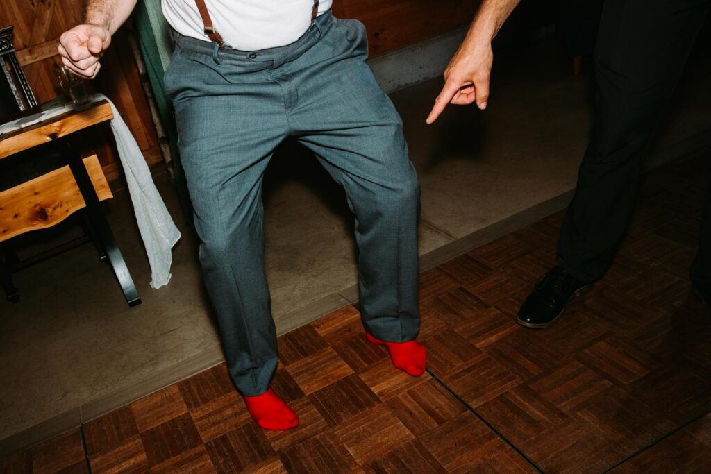 Groom solo dancing and pointing to the crowd, Red Sox socks and suspenders, full personality, Bluebird Farm reception