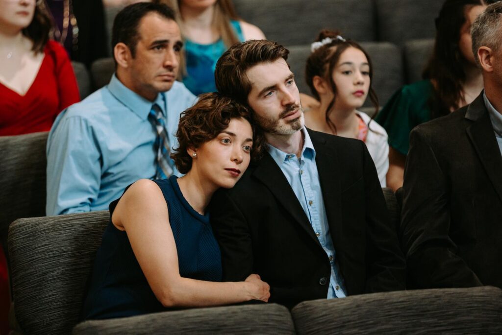 Wedding guests with emotional expressions watching the ceremony, couples leaning into each other