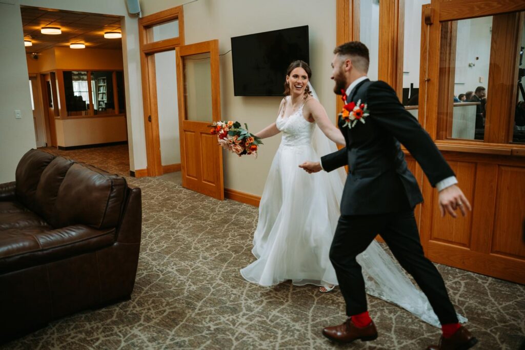Bride and groom running and celebrating in the church lobby right after the ceremony, groom's Red Sox socks visible