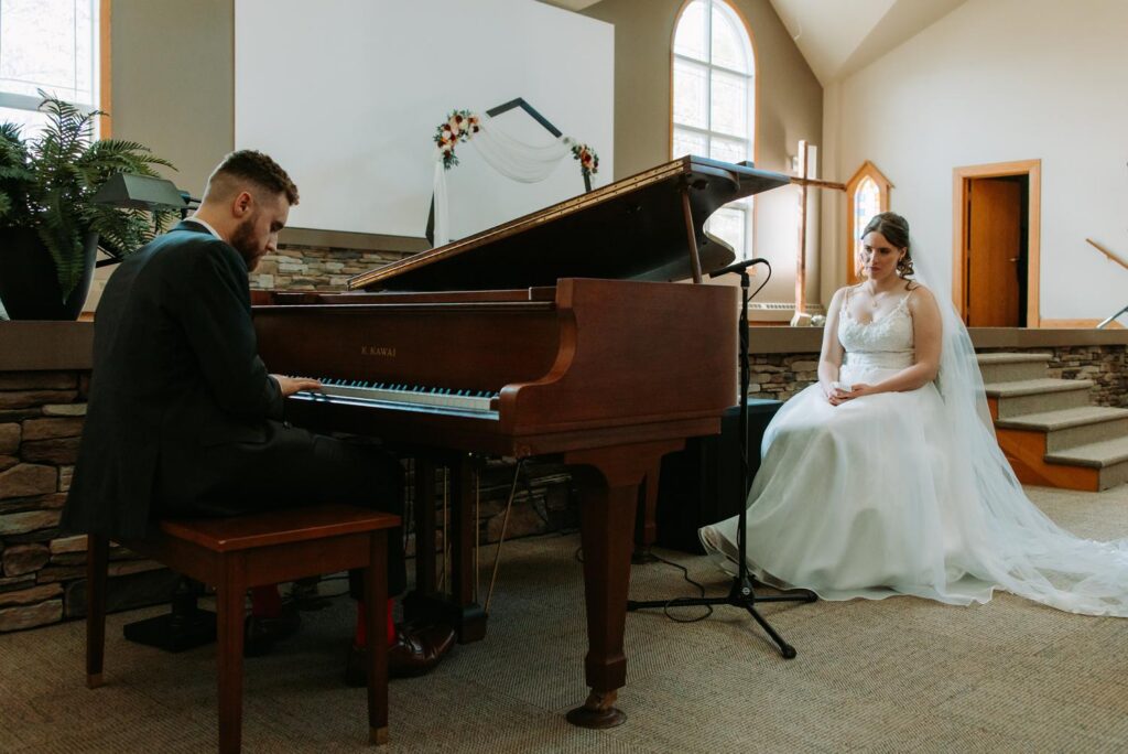 Groom Tim playing a grand piano while bride Erin watches in her wedding dress, the surprise Married Life from Up moment, Bluebird Farm