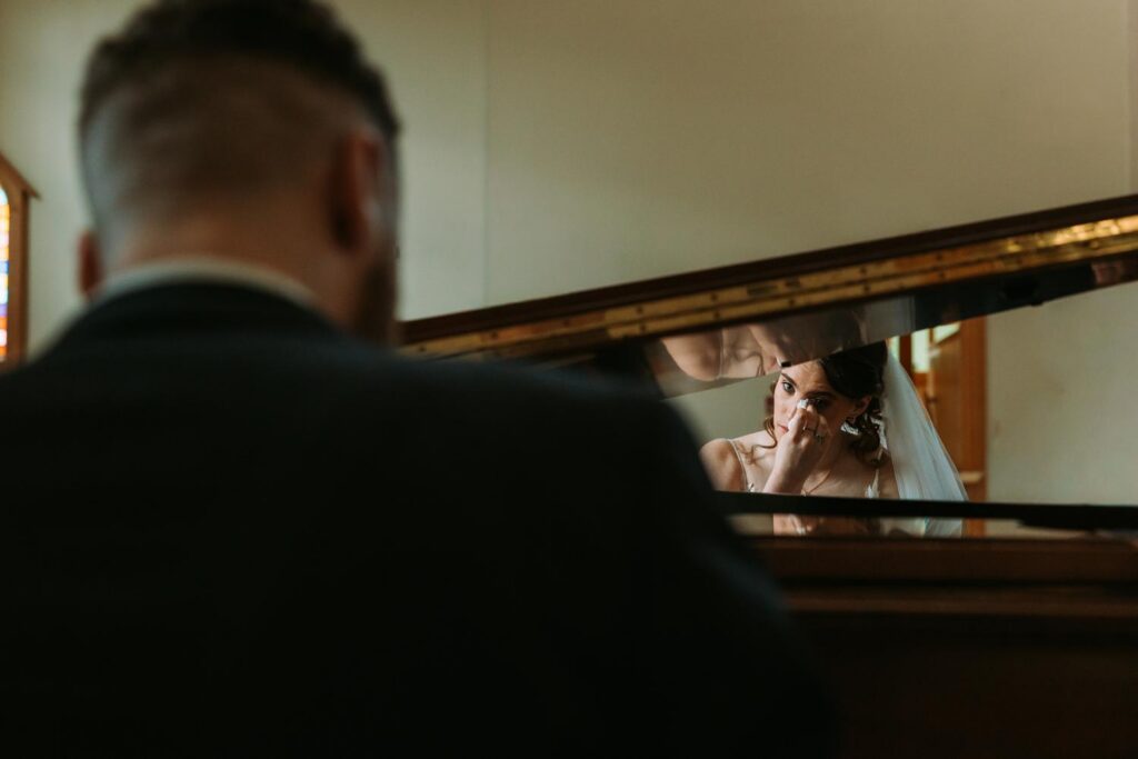 Groom Tim from behind at the grand piano, playing his surprise medley for the bride after the ceremony