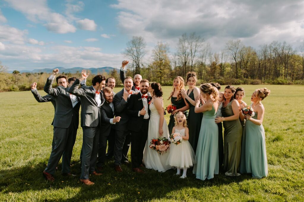 Full wedding party in the open field at Bluebird Farm with Catskill Mountains in the background, sage green and white