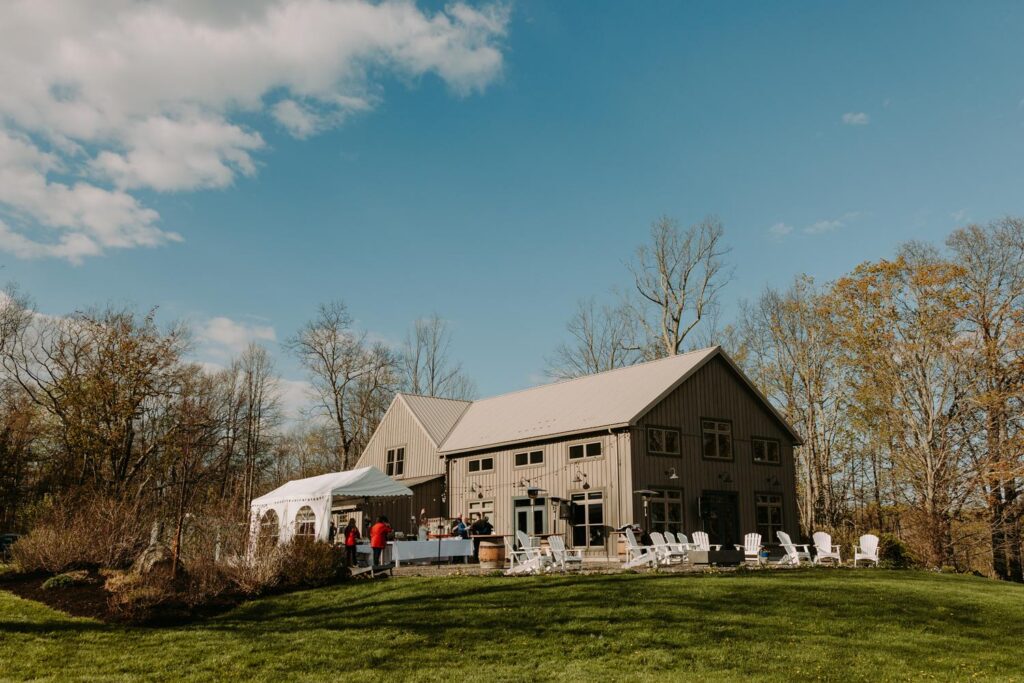 Wide exterior shot of Bluebird Farm barn under a blue sky with spring green fields, Medusa New York