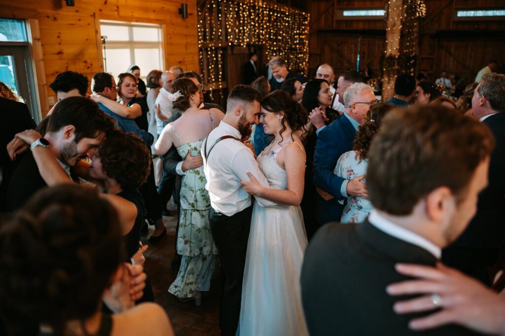 Full dance floor packed with guests celebrating inside the Bluebird Farm barn, high energy reception
