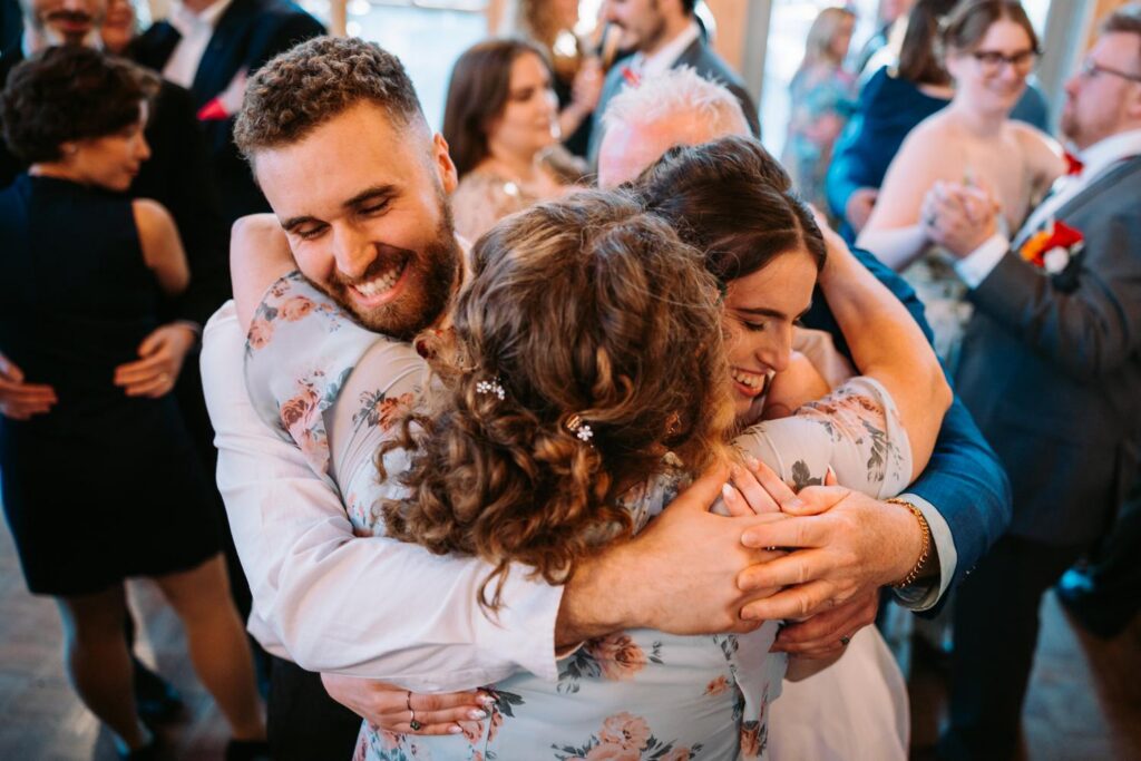 An emotional group hug on the dance floor, candid documentary wedding moment
