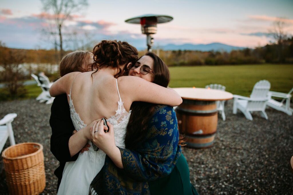 Bride hugging guests outside on the patio at dusk, Bluebird Farm wedding