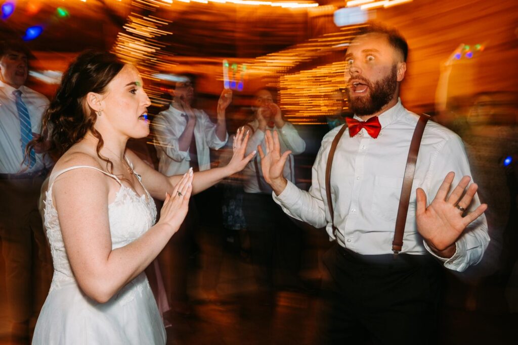Motion blur of bride and groom dancing together inside the Bluebird Farm barn, colorful lights