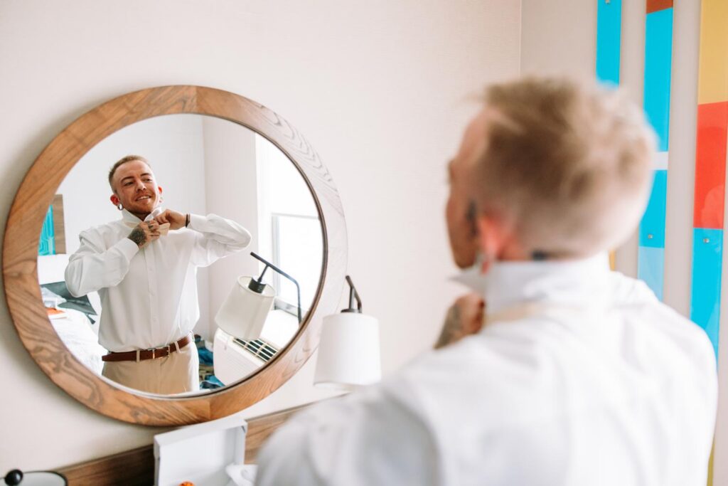 Sabin getting ready and adjusting his collar in a circular mirror, colorful Best Day Ever wall art in the background, Hampton Inn New Haven