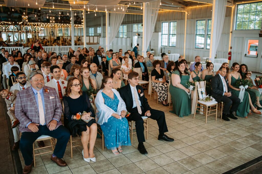 Wide shot of full guest seating during the ceremony at Lighthouse Point Park, teal bridesmaid dresses visible throughout the room